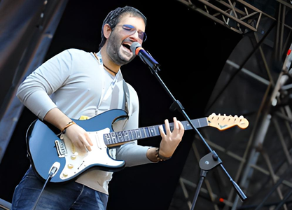 Dario Sgrò chante et joue de la guitare électrique sur une scène.