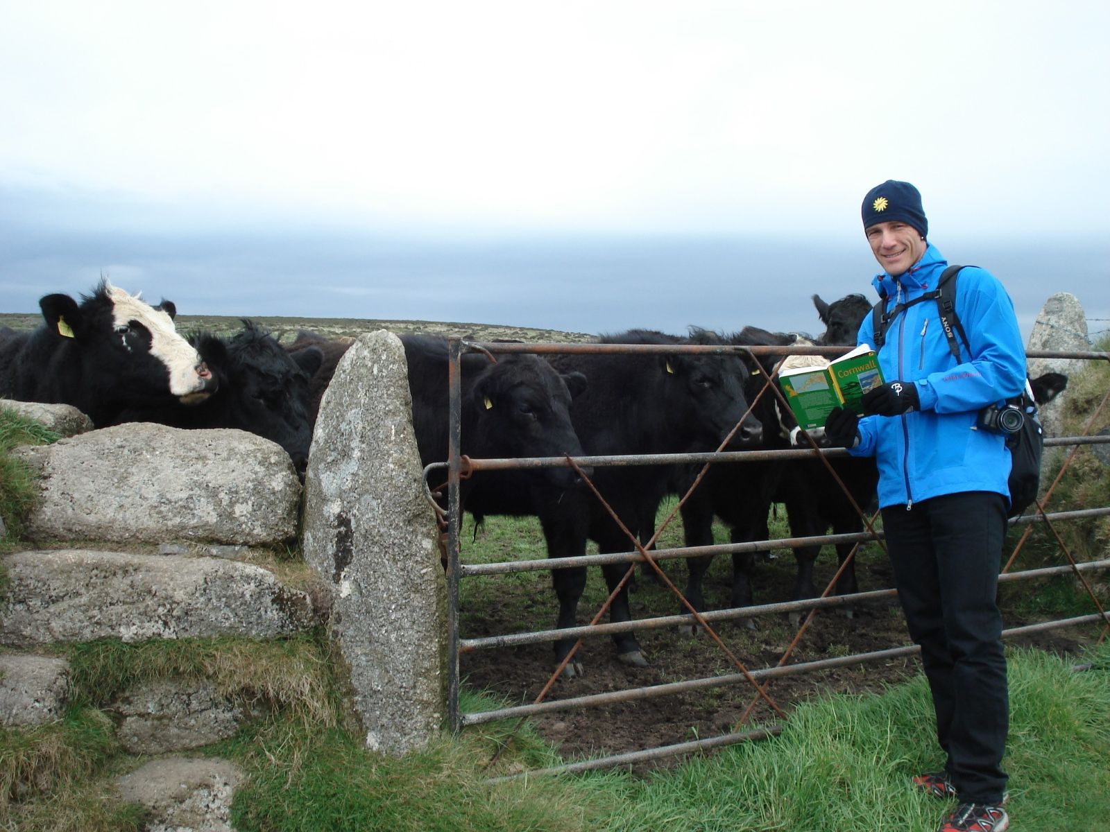 Andrew Bond en tenue d'extérieur dans le nord de l'Angleterre devant une barrière menant à un pâturage de bovins